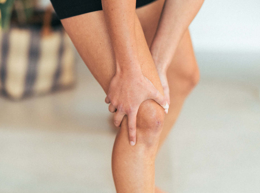 A woman holding her knee in discomfort due to joint pain