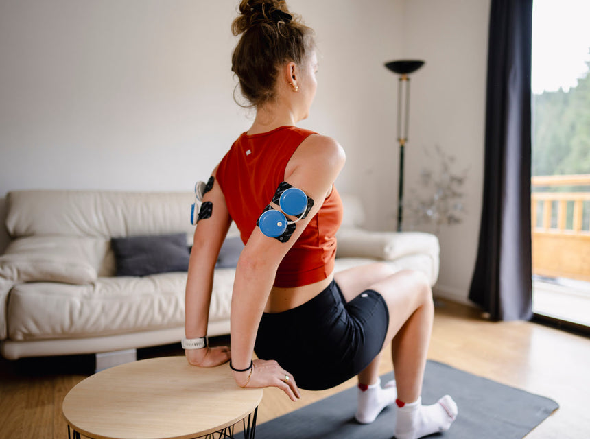 A woman exercising her arms using the Compex FIT 5.0 muscle stimulator