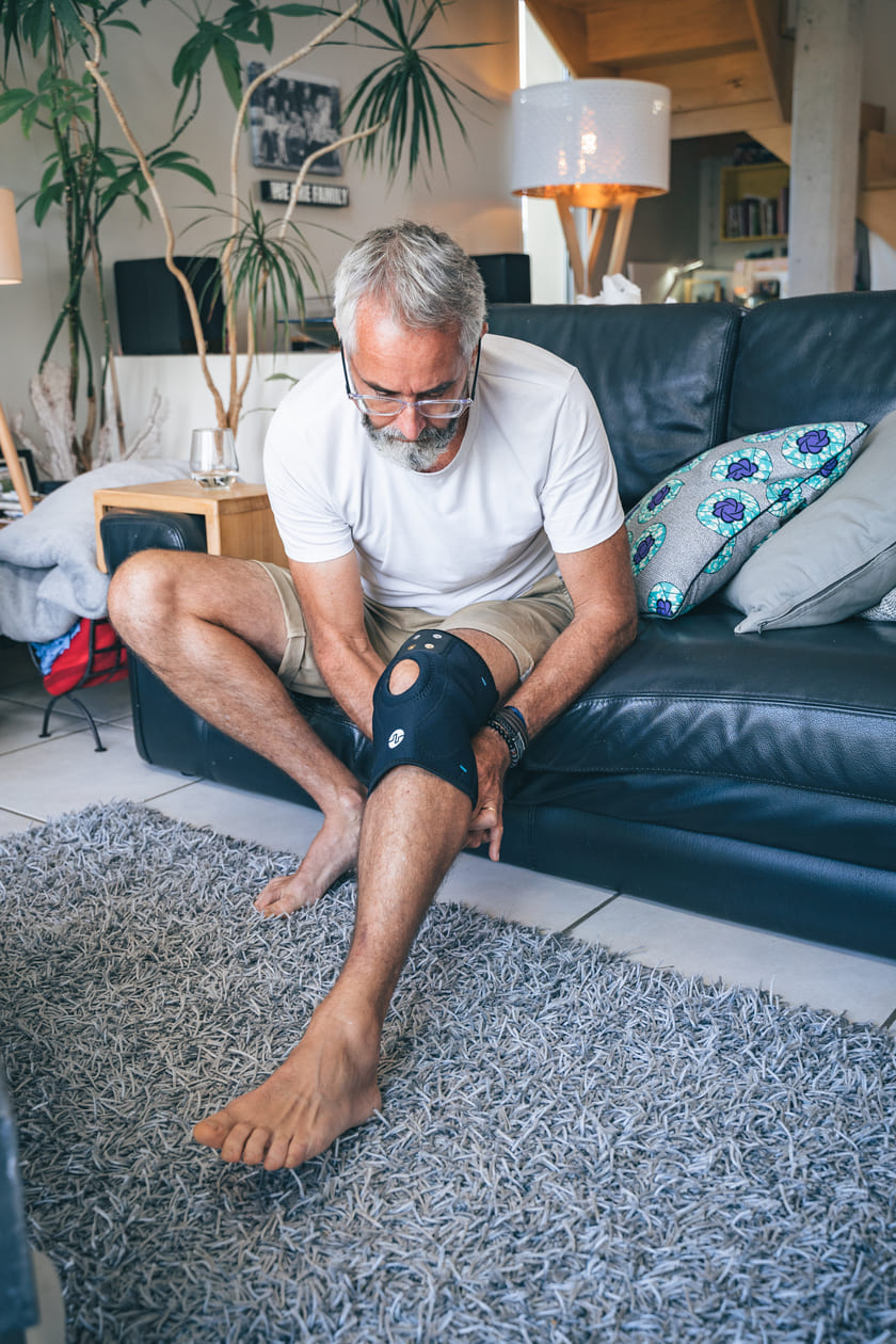 A man using the Compex ComfortTENS Knee™ Wrap to relieve his knee pain