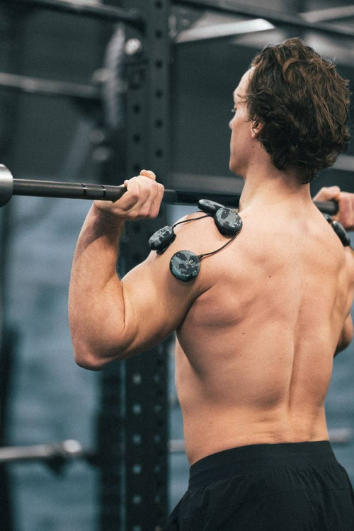 A man lifting an olympic bar using the Compex SP 8.0 WOD Edition EMS muscle stimulator for a shoulder muscle strengthening session
