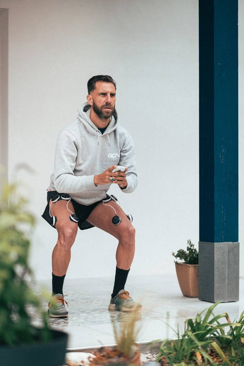 A man using the Compex SP 8.0 EMS muscle stimulator for a quad muscle strengthening session