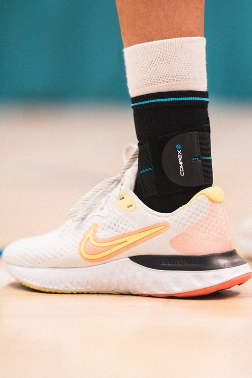 A man playing basketball, wearing the Compex Activ'® Ankle+ support