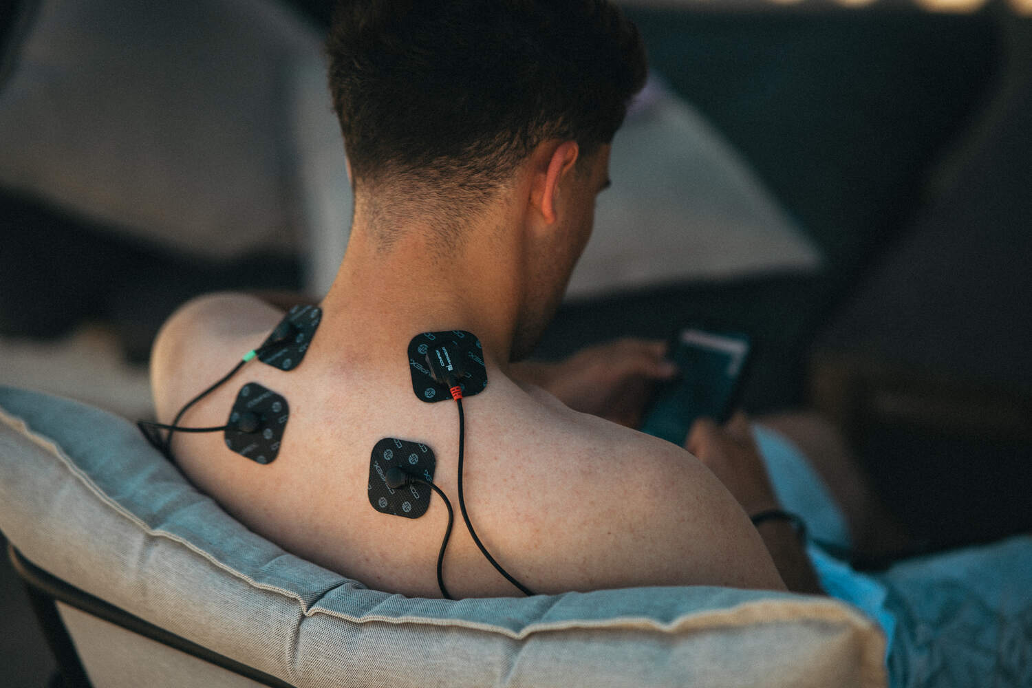 A man using a wired Compex EMS muscle stimulator