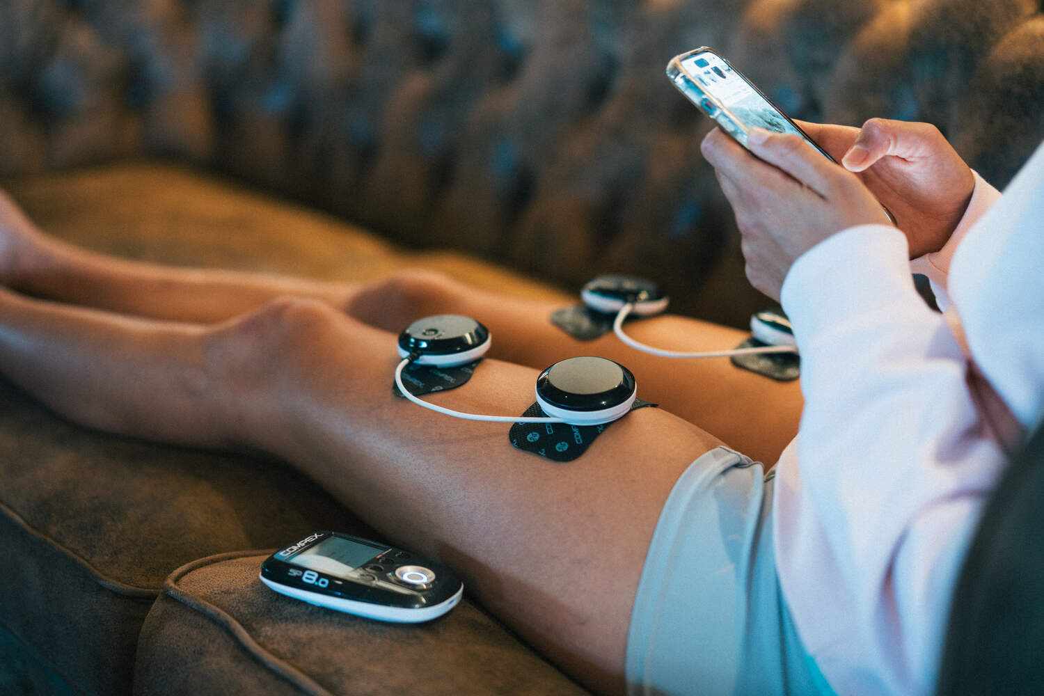 A woman using a wireless Compex EMS muscle stimulator