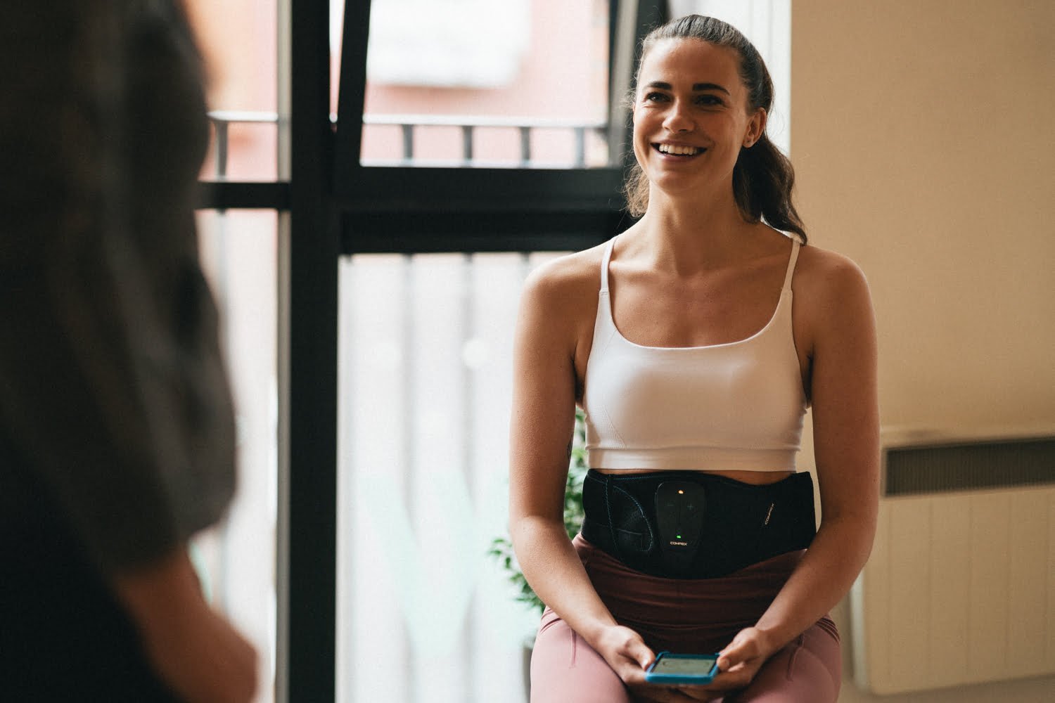 A women enjoying improving her abs using Compex Corebelt