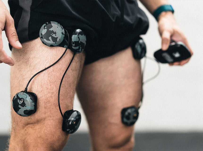Un homme qui a des électrodes compex sur ses quadriceps pour travailler avec l'électrostimulation