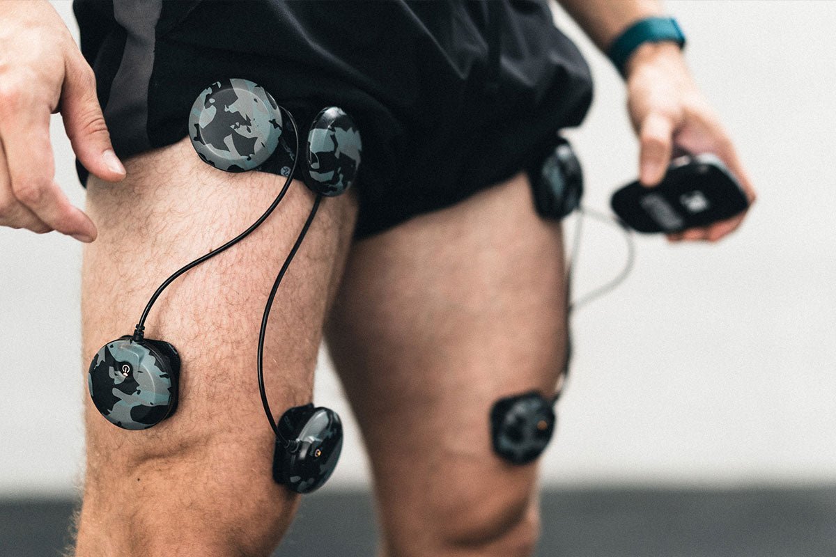 Un homme qui a des électrodes compex sur ses quadriceps pour travailler avec l'électrostimulation