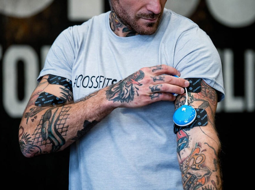 Un homme qui utiliser l'électrostimulation Compex sur ses biceps pour développer leur taille