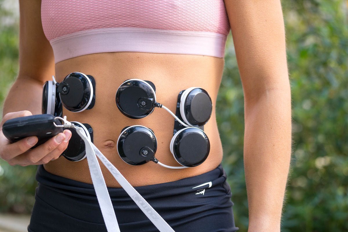Une femme qui a les électrodes Compex sur ses abdos pour les muscler avec l'électrostimulation