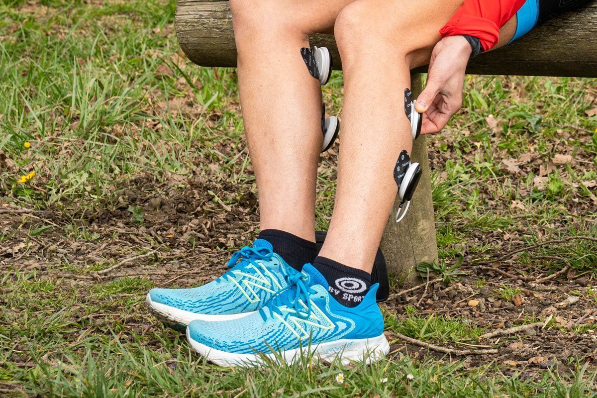 Une femme qui utilise l'électrostimulation sur ses mollets pour prévenir ses cramps
