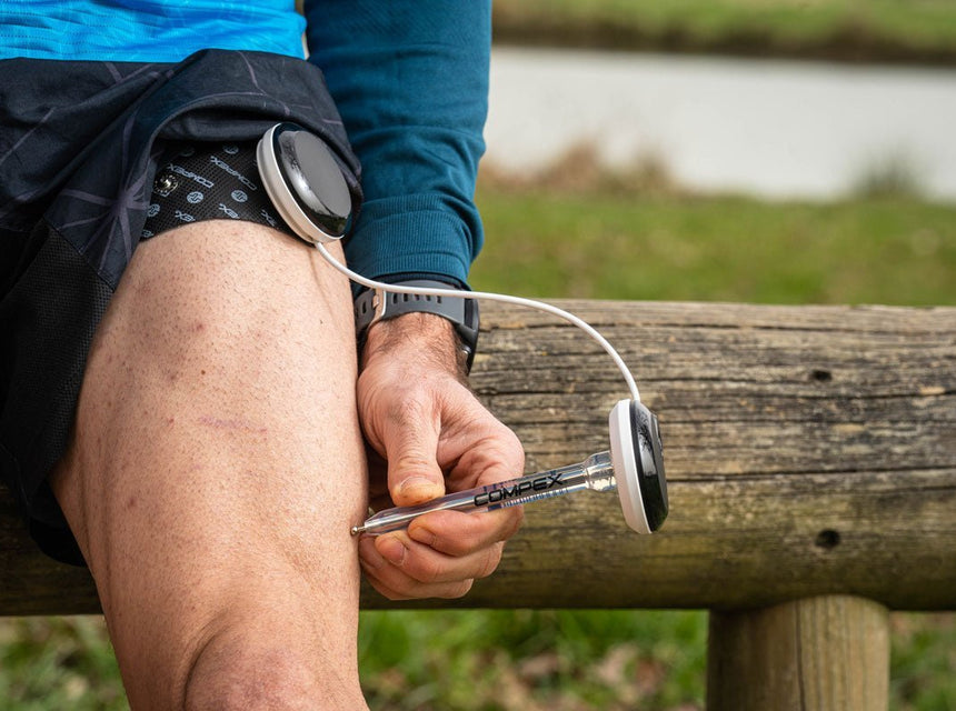 Une homme qui utilise le stylet point moteur Compex sur son quadriceps