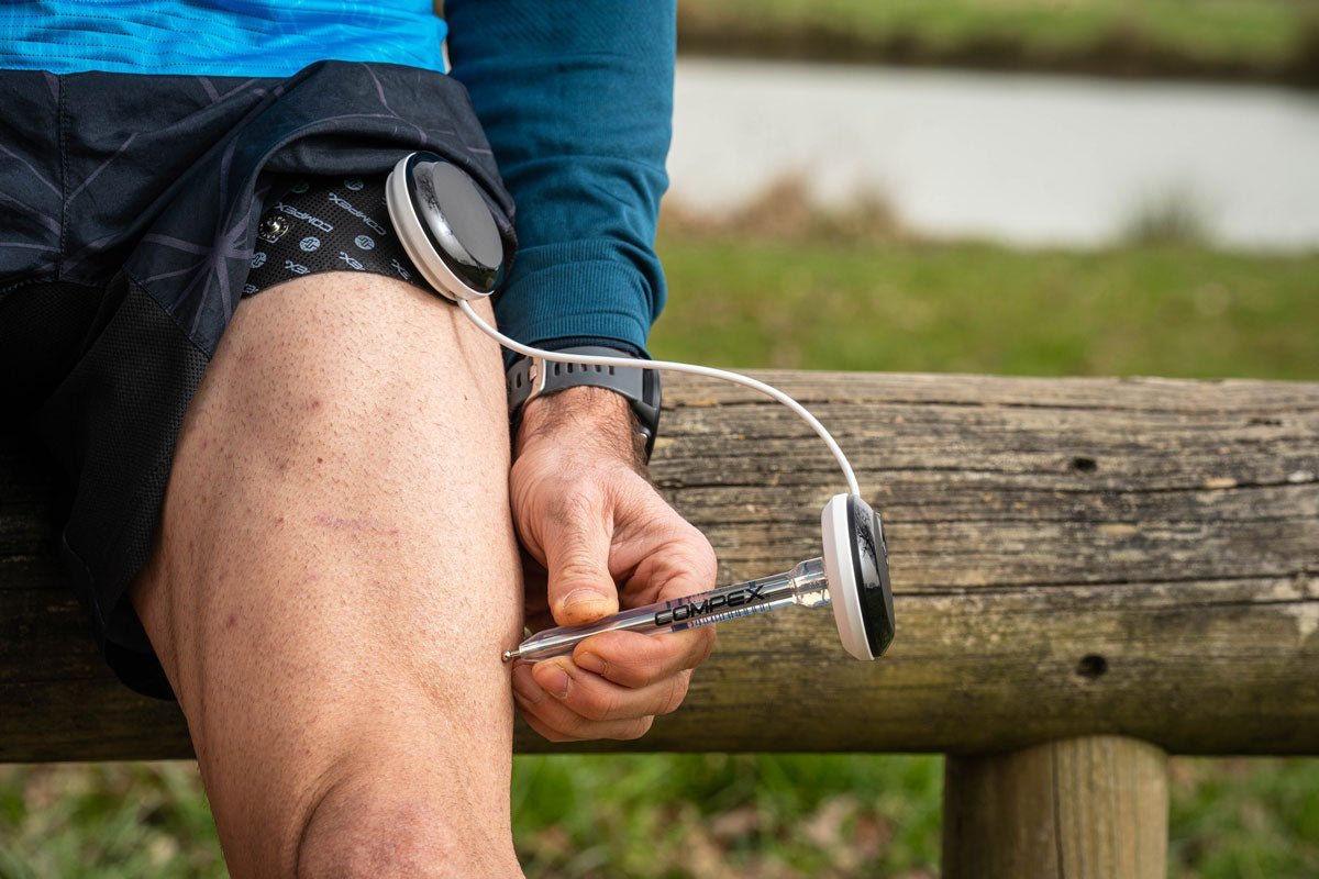 Une homme qui utilise le stylet point moteur Compex sur son quadriceps