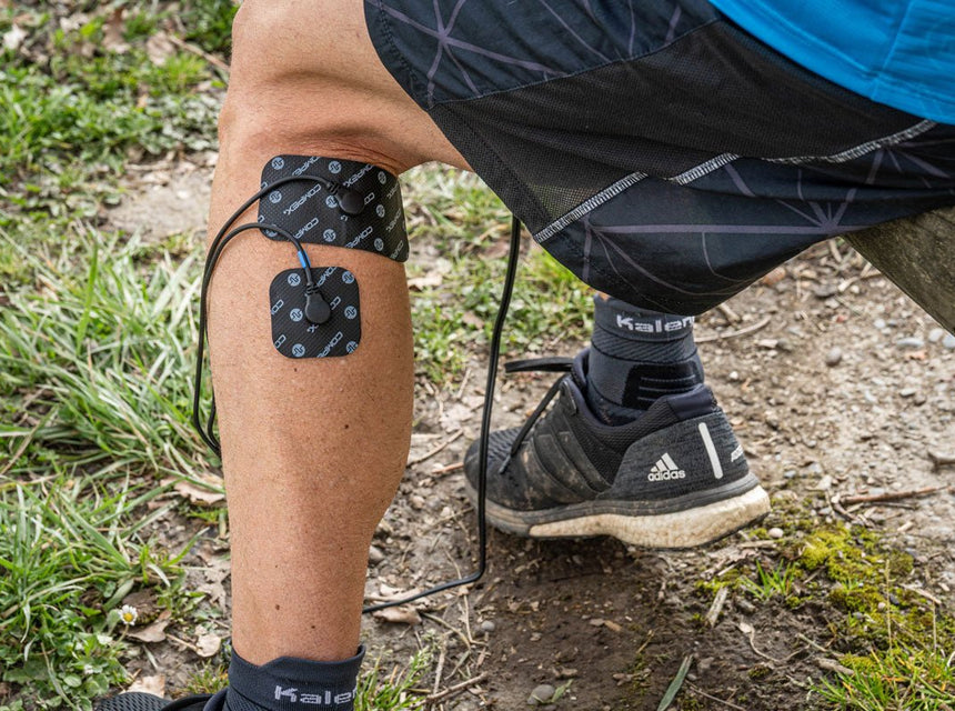 Un homme qui a les électrodes Compex sur son mollet pour gérer sa contracture musculaire