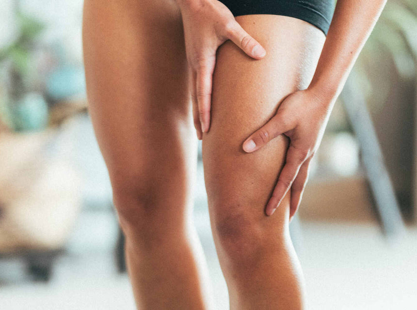 A woman holding her quad muscle in discomfort