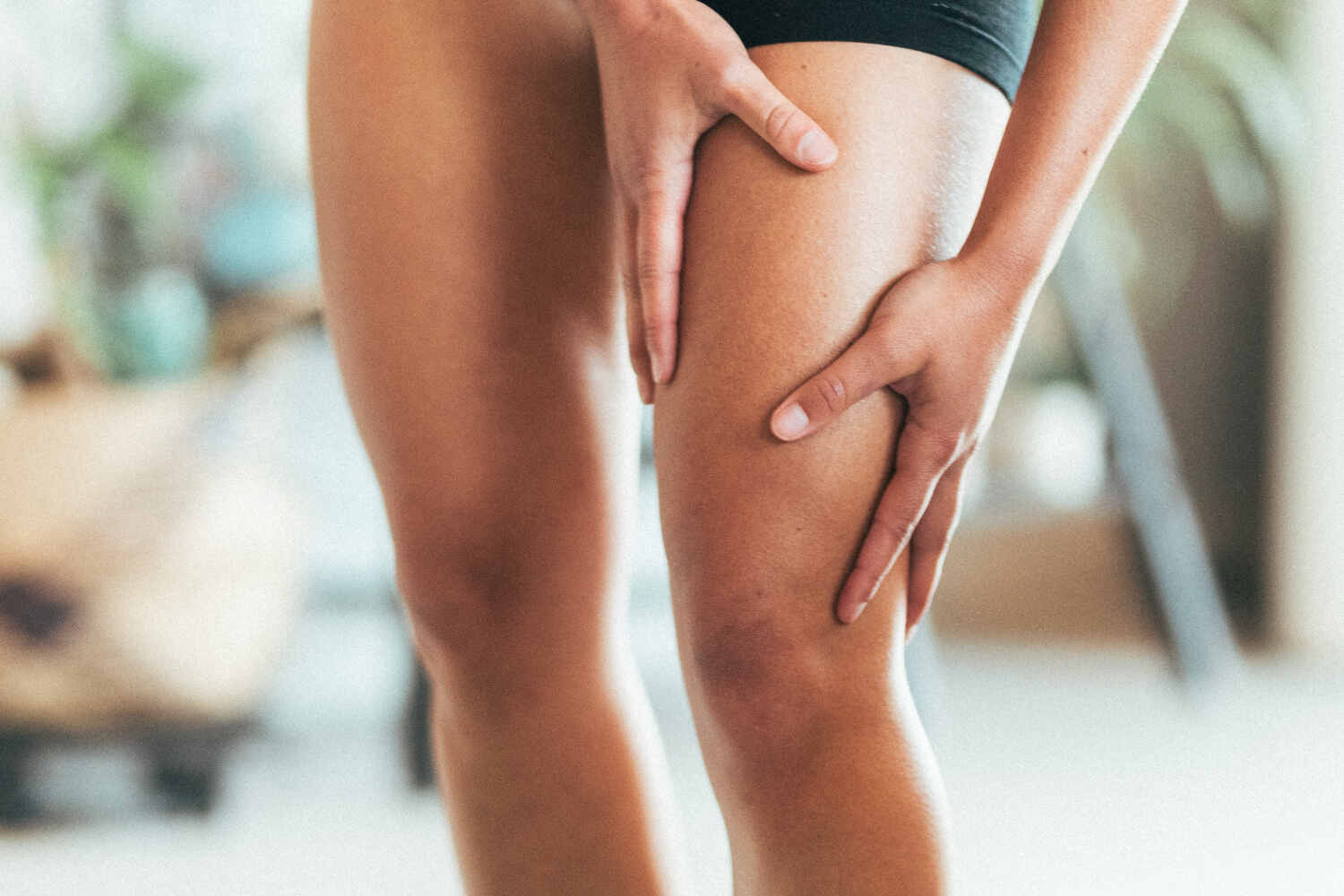 A woman holding her quad muscle in discomfort