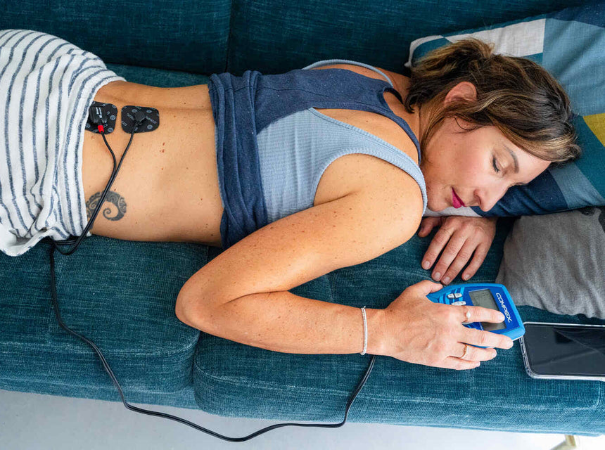A woman using the Compex FIT 3.0 electrostimulator to treat Lumbago