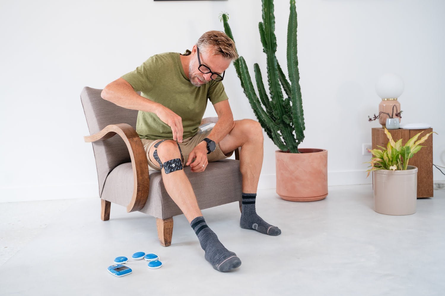 A man preparing to treat patellar tendinopathy with the Compex FIT 3.0 electrostimulator