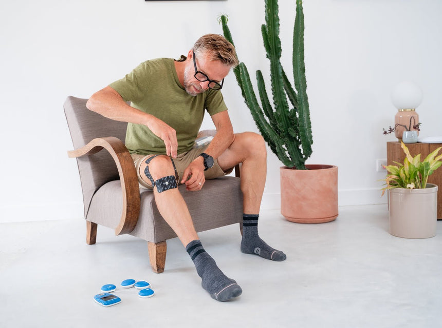 A man preparing to treat patellar tendinopathy with the Compex FIT 3.0 electrostimulator