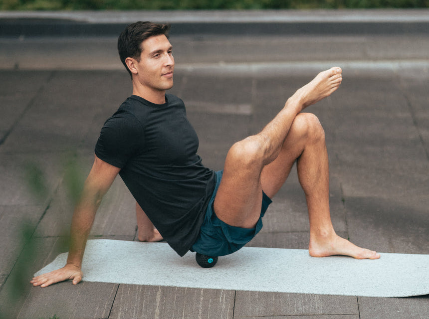 A man massaging his glutes using the Compex Molecule vibrating massage ball