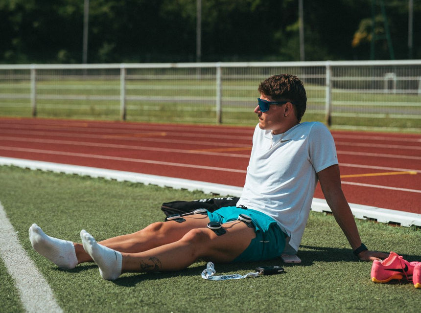 un homme qui aide ses jambes à récupérer après sa course avec un électrostimulateur compex