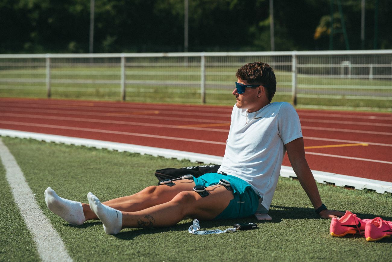 un homme qui aide ses jambes à récupérer après sa course avec un électrostimulateur compex