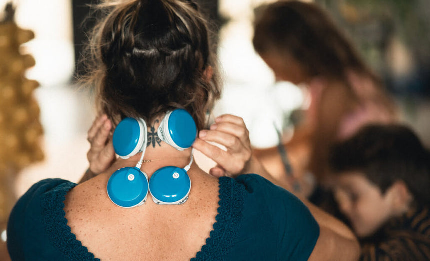 Une mère en train d'utiliser le programme TENS du stimulateur musculaire Compex FIT 5.0 pour soulager ses douleurs cervicales