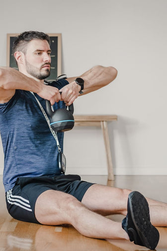 A man strengthening his shoulders using the Compex SP 8.0 EMS muscle stimulator and a kettlebell