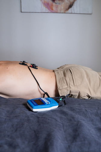 A man relieving back pain using the Compex FIT 3.0 EMS muscle stimulator