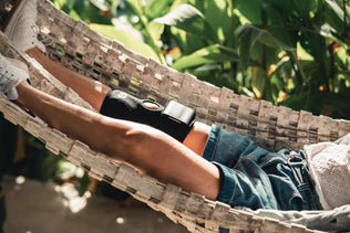 A woman relaxing in a hammock, using the Compex ComfortTENS Knee™  to relieve knee pain