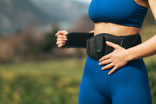 A woman putting on the Compex Corebelt EMS muscle stimulator belt