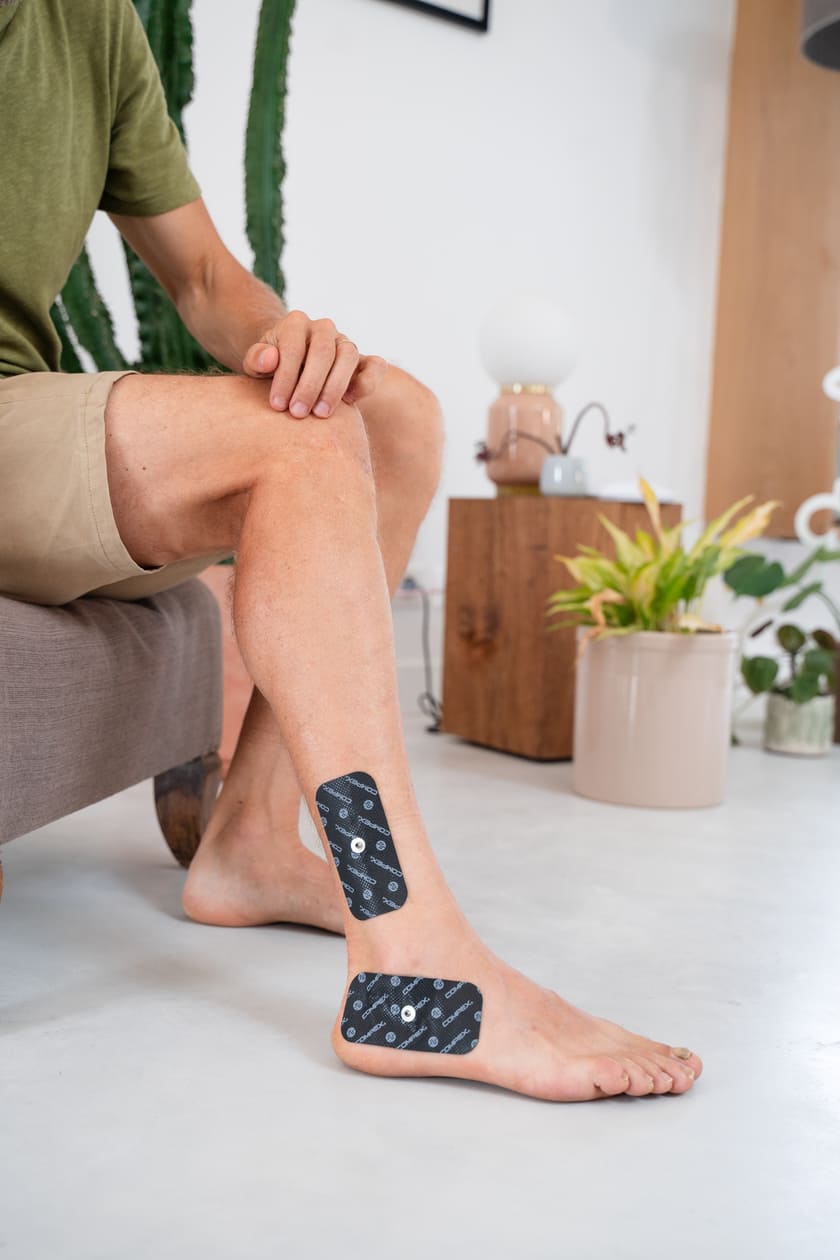 A man applying Compex electrodes to his ankle