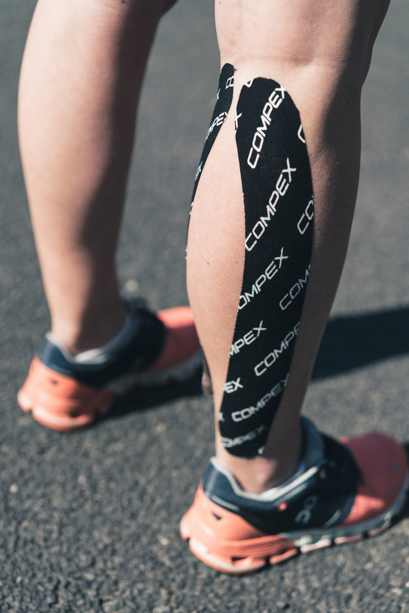 A woman with black Compex Tape on her calf muscle
