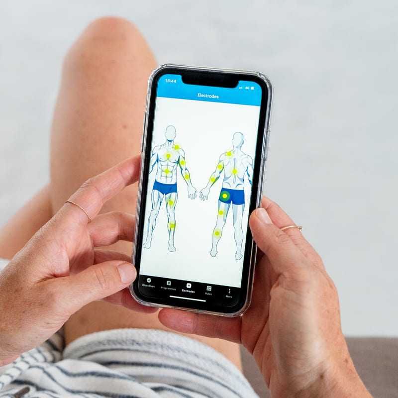 A woman using the Compex Coach App to view electrode placement