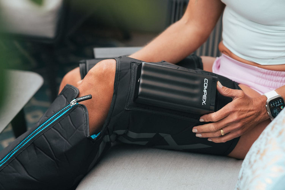 A woman adjusting the Compex Ayre™ Pro compression boots