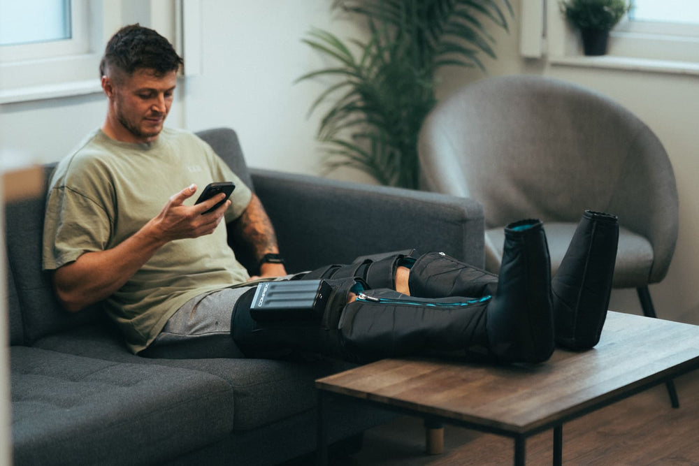A man using the Compex Ayre™ Pro compression boots to heal his leg muscles