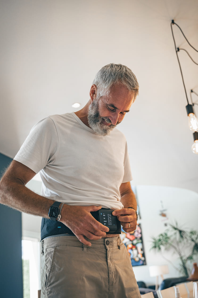 A man turning on the Compex ComfortTENS Back wrap