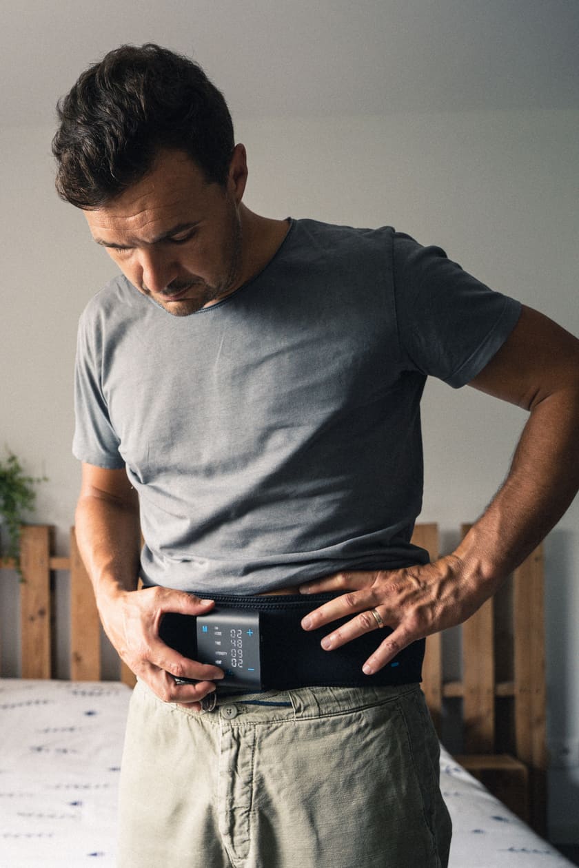 A man turning on the Compex ComfortTENS Back wrap