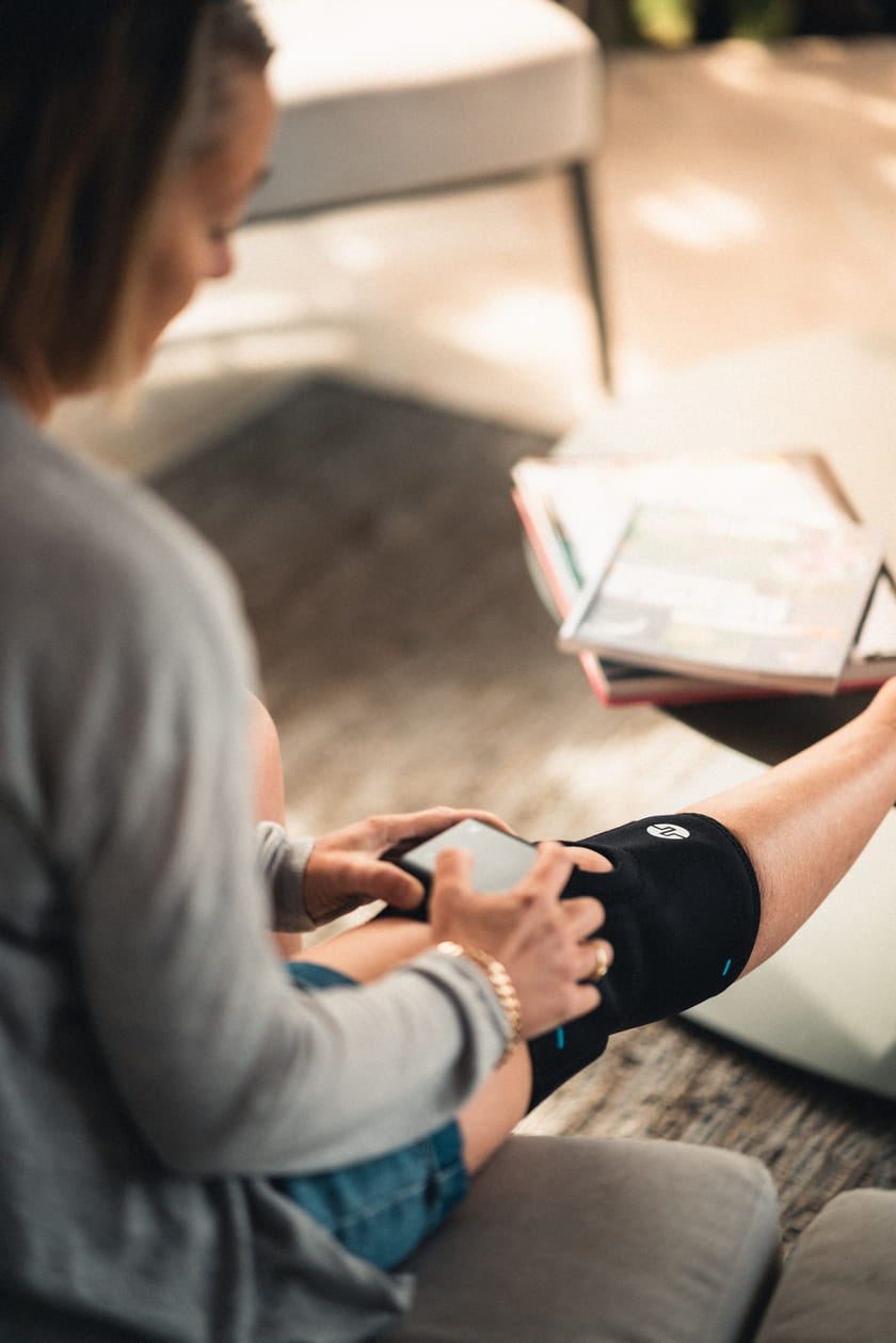 A woman putting on the Compex ComfortTENS Knee wrap