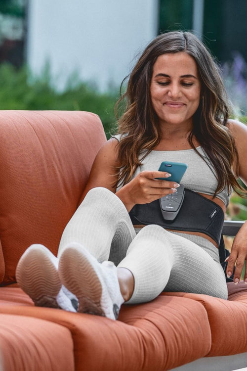 A woman using the Compex Corebelt 1.0 EMS muscle stimulator belt