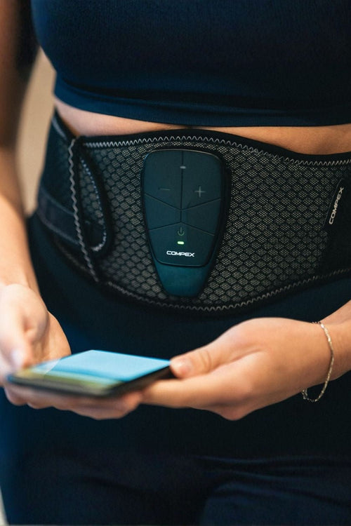 A woman using the Compex Corebelt 3.0 EMS muscle stimulator belt