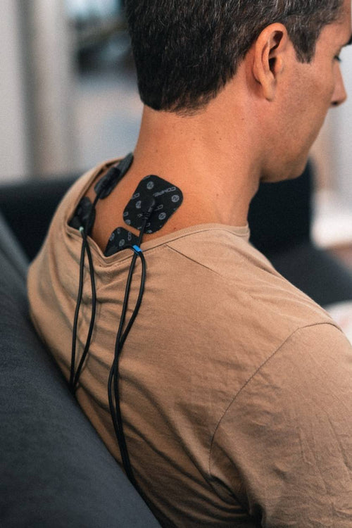 A man using the Compex FIT 1.0 EMS muscle stimulator for a neck massage session