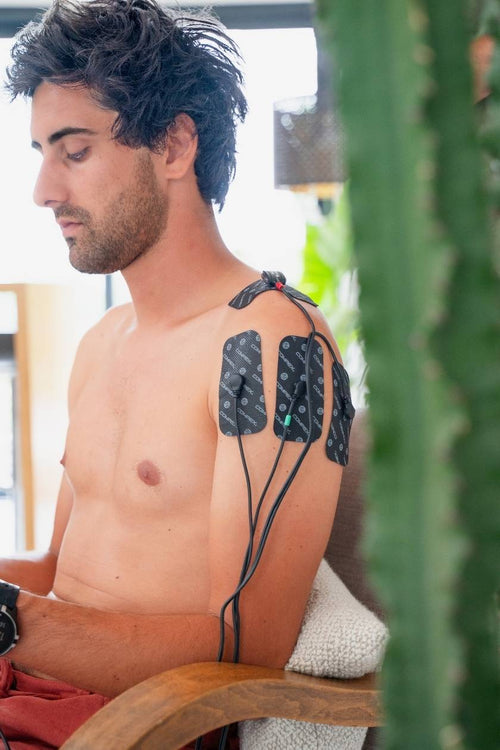 A man using the Compex FIT 3.0 EMS muscle stimulator for a shoulder pain relief session