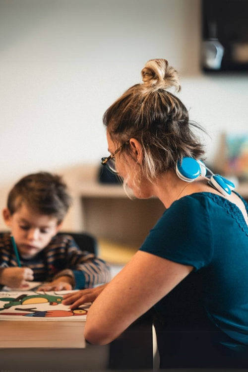 A woman sitting with her child using the Compex FIT 5.0 EMS muscle stimulator for a neck pain relief session