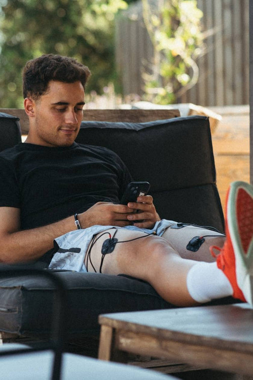 A man using the Compex SP 4.0 EMS muscle stimulator for a quad muscle recovery session