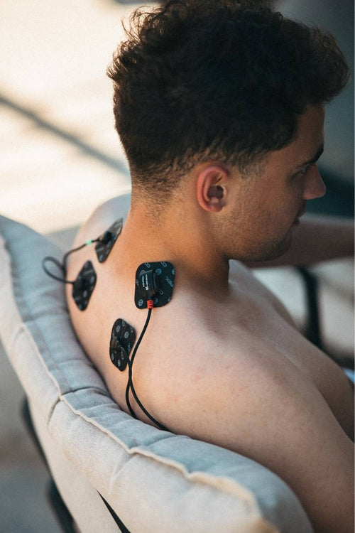 A man using the Compex SP 4.0 EMS muscle stimulator for a neck massage session