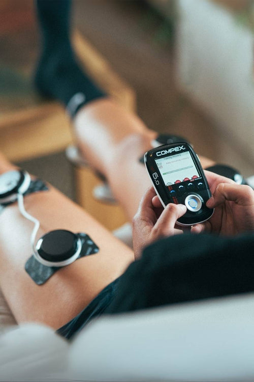 A man using the Compex SP 6.0 EMS muscle stimulator for a quad muscle recovery session