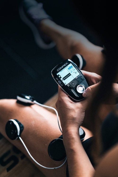A woman using the Compex SP 8.0 EMS muscle stimulator for a quad muscle recovery session