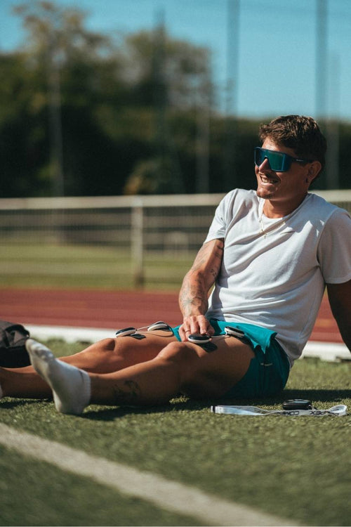 A man using the Compex SP 8.0 EMS muscle stimulator for a quad muscle recovery session