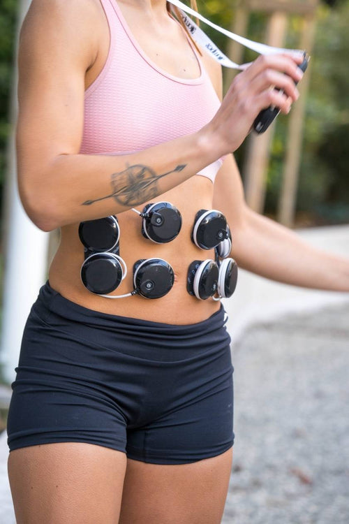 A woman using the Compex SP 8.0 EMS muscle stimulator for an ab muscle strengthening session