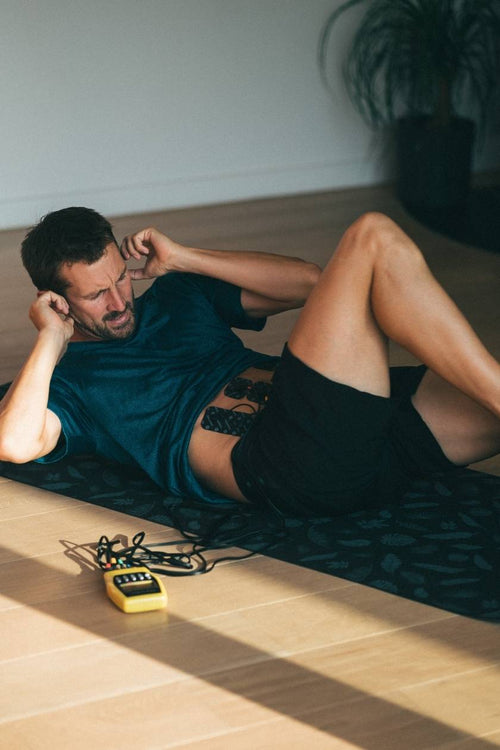 A man using the Compex Fitness EMS muscle stimulator for am ab muscle strengthening session